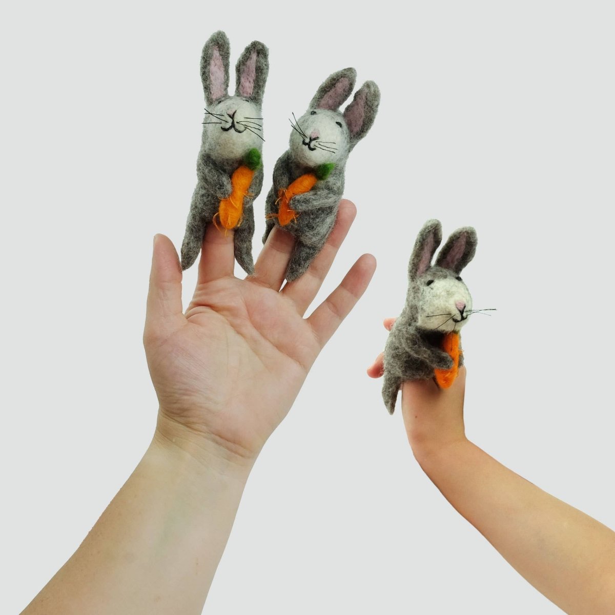 Handcrafted grey rabbit finger puppet made from natural wool, featuring pink ears and a white fluffy tail.