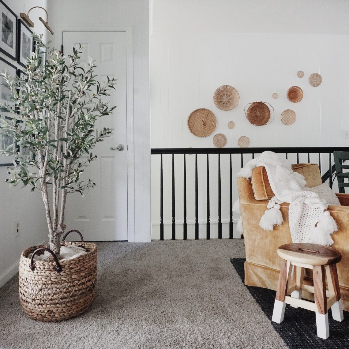 Cozy living room with a brown armchair, wooden stool, and decorative wall elements.