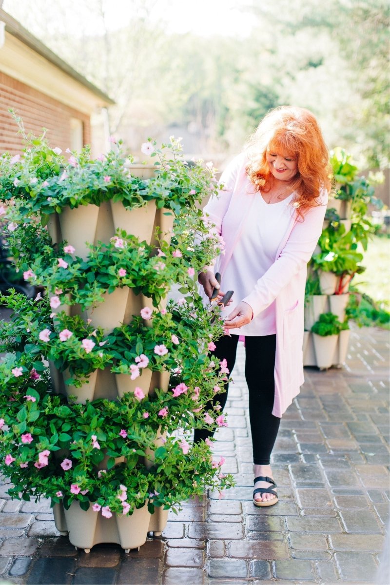Woman standing next to 5-Tier GreenStalk Original Vertical Planter in Stone – Basic Texture tower planter for small-space gardening.