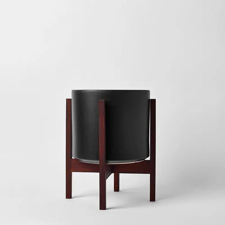 Black planter with wooden base on a white background