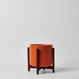 Ceramic planter with wooden stand on a light gray background