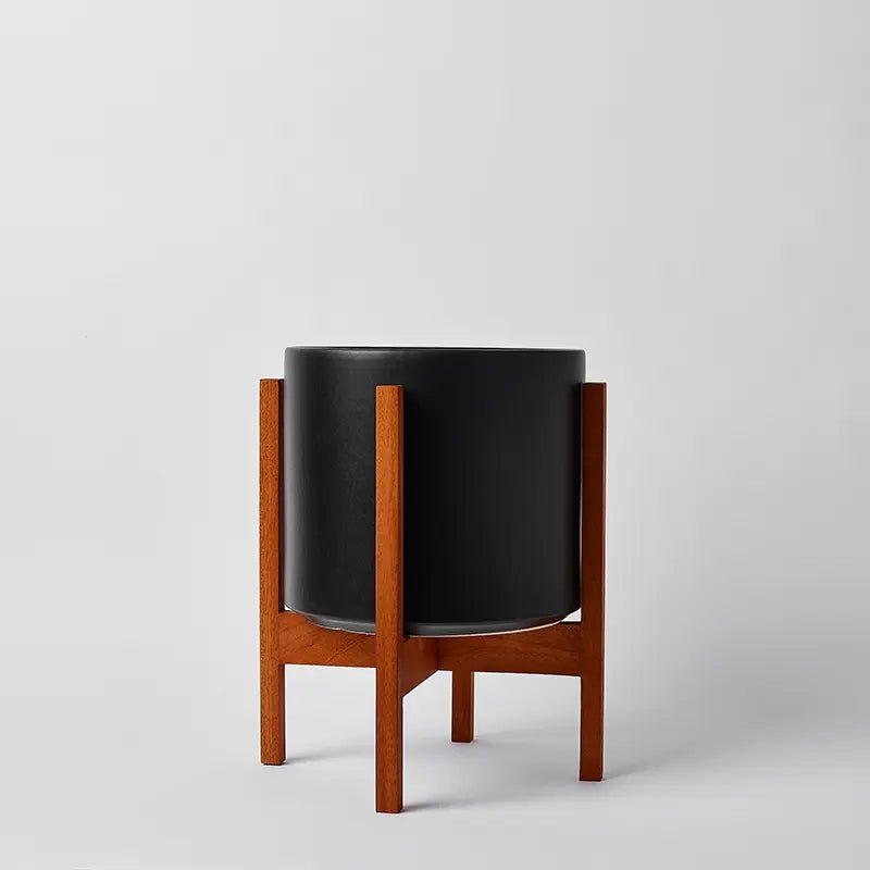 Black planter with wooden stand on a light gray background