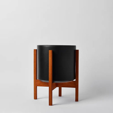 Black planter with wooden stand on a light gray background