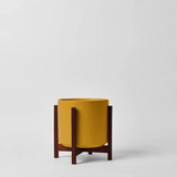 Yellow planter with wooden stand on a light gray background