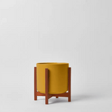 Yellow planter with wooden stand on a light gray background