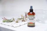 Air plant food spray bottle on a white surface with air plants in the background