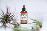 Bottle of Air Plant Shop air plant food spray with air plants in the background