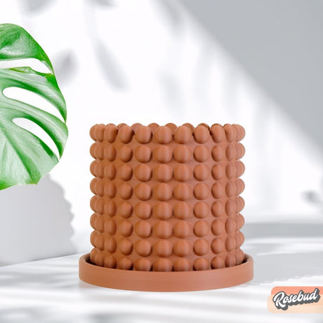Brown textured pot on a white background with a plant leaf in the corner