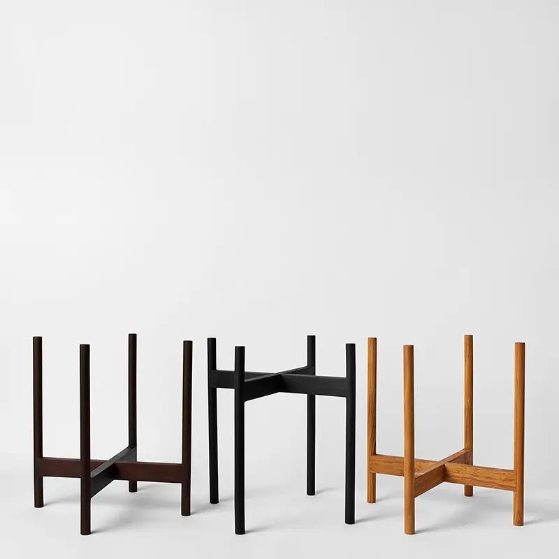Three minimalist plant stand designs in different colors on a white background