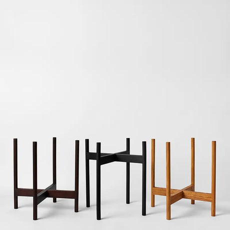 Three minimalist plant stand designs in different colors on a white background